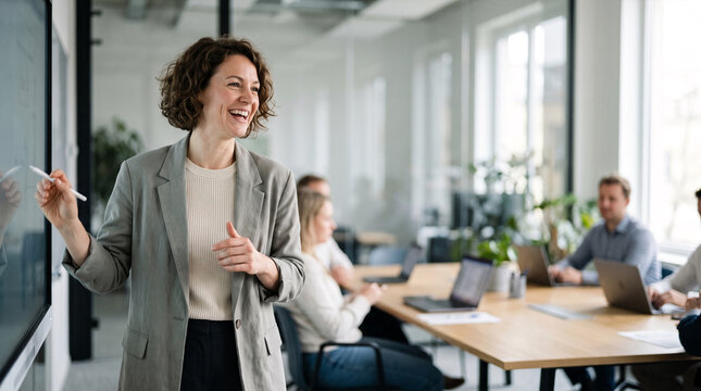 Woman leading business meeting pointing at digital screen in modern office
