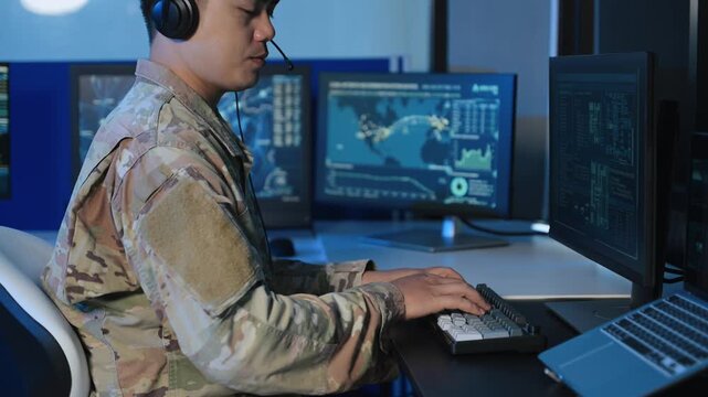 Military operator with headset analyzes radar HUD screens and takes notes in high tech command center