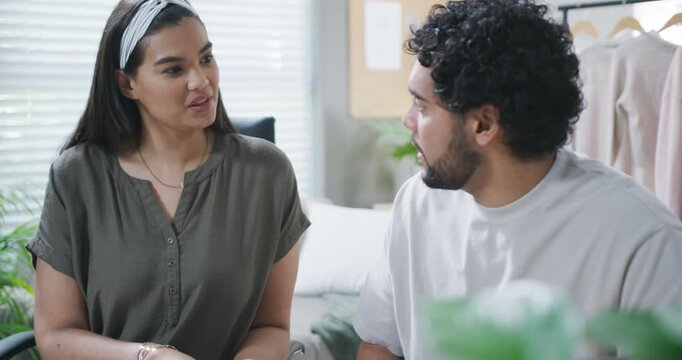 Couple on sofa at home, woman speaking first while man leaning, listening, discussing issue