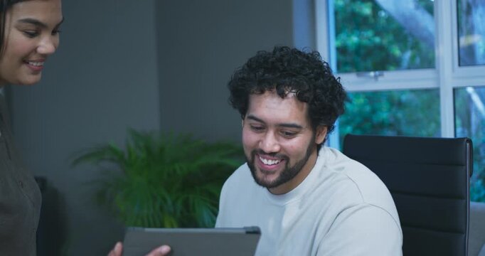 African American team woman presenting tablet, seated man leaning forward reviewing draft in chair