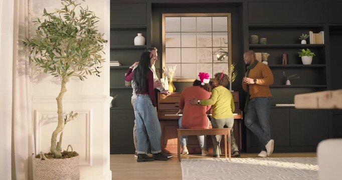 Diverse family approaching upright piano at home with Santa hat and antlers celebrating holiday