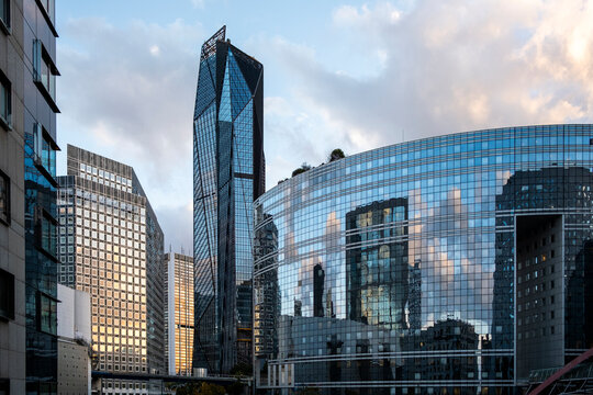 Modern glass buildings and reflective architecture in Paris France form a dense urban business district with geometric facades and dramatic sky