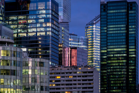Dense modern office buildings and glass architecture in Paris France create a layered urban business skyline with illuminated windows at blue hour