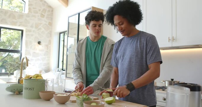 African American men prompted by fruit cutting at kitchen island into bowls for snack