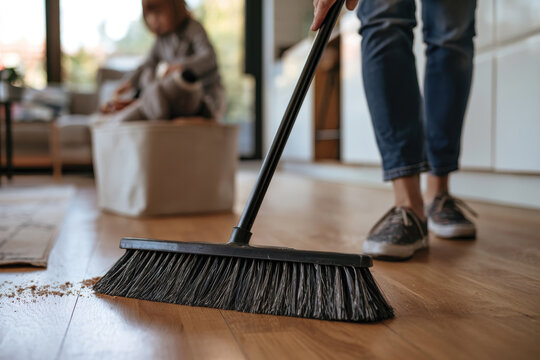 A person sweeps the floor in a bright room, showcasing the importance of cleanliness and the emotions linked to maintaining a tidy space, promoting well-being and comfort.