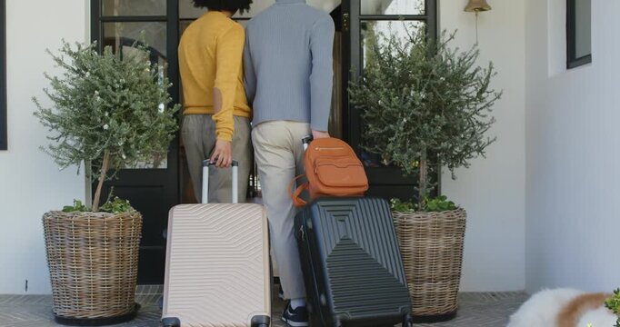 Pause ending as two adults are pushing open front door walking inside pulling suitcases going home