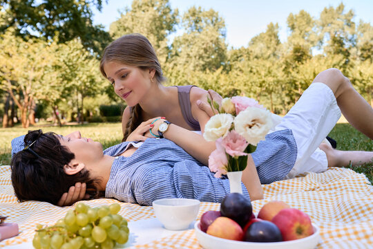 Happy lovers relax on a picnic blanket, sharing snacks and sweet moments together