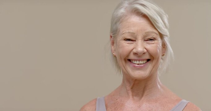 Senior female seeing camera, smiling, widening, laughing with stud earrings, tank top in studio