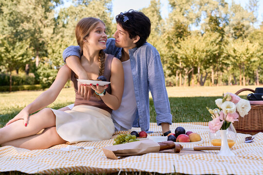 Joyful lovers share a picnic in a vibrant park, surrounded by natures beauty