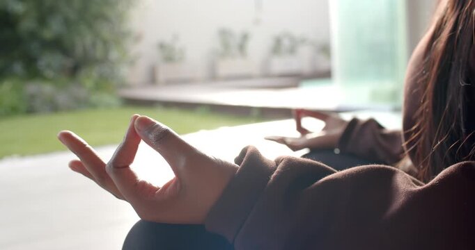 Hands are forming meditation mudra and making small adjustments while settling by open sliding door