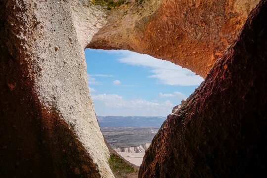 Cappadocia valley view framed by ancient cave opening and stone window
