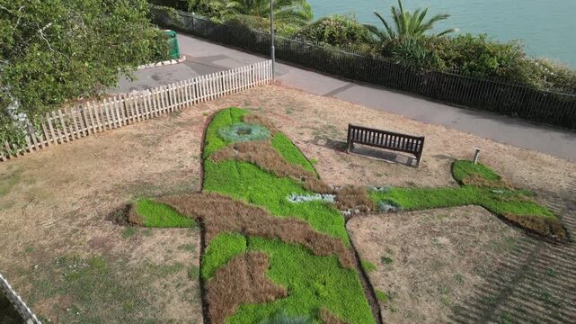 Paignton, Devon, England: DRONE VIEWS: A floral arrangement in the shape of a Spitfire in honour of RAF pilot, Flight Lt Frederick Denston. The surrounding grass has been burnt in the 2026 drought.