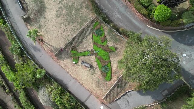 Paignton, Devon, England: DRONE VIEWS: A floral arrangement in the shape of a Spitfire in honour of RAF pilot, Flight Lt Frederick Denston. The surrounding grass has been burnt in the 2026 drought.