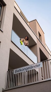 Frau putzt Balkongel&auml;nder aus Glas in Untersicht
