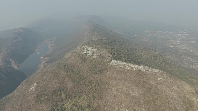 Aerial view flying along a dry hill ridge in morning haze, Rajgir hills, Bihar, India