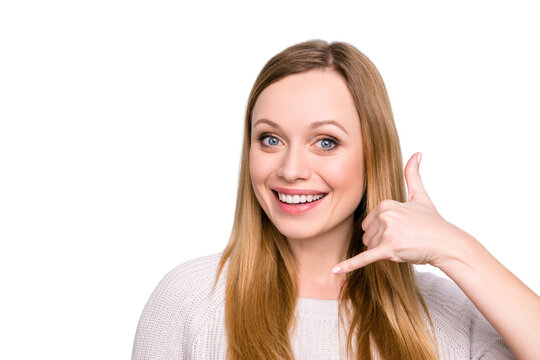 Portrait of friendly cute girl with beaming smile gesturing telephone sign with fingers near ear, asking for call isolated on grey background