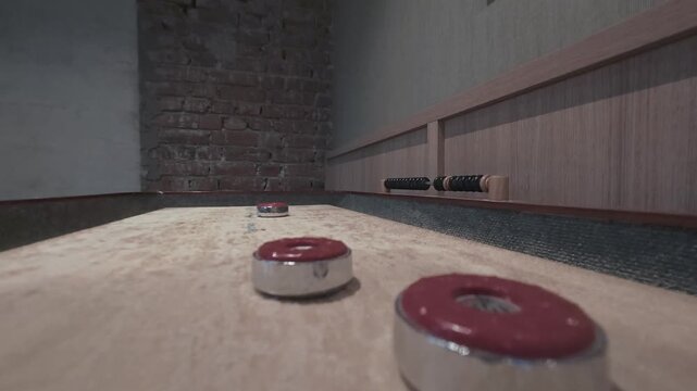 Three red shuffleboard pucks resting on the polished wooden board