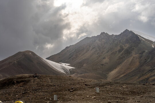 Evening view of Yukhin Peak and nearby hill under dramatic gray evening sky in Kyrgyzstan