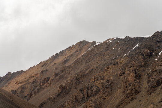 Evening view of Yukhin Peak's rocky ridge under gray sky, Lenin Camp 1