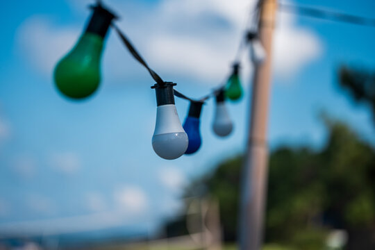Colorful string lights decorating outdoor space against blue sky