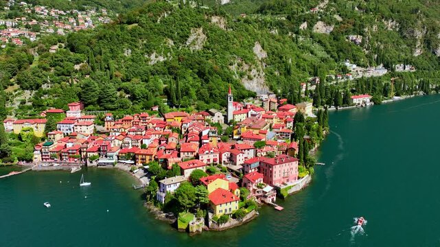 Drone flying above a historic Italian town of Varenna on lake Como, aerial shot of Varenna with colorful historic houses and church, luxury vacation in Italy
