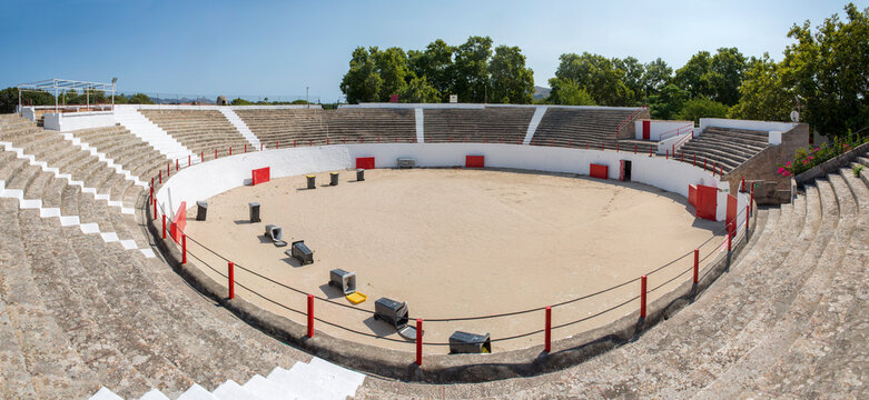 Interior of the plaza de toros bullring in Alc&uacute;dia, on the island of Mallorca, Balearic Islands, Spain, showing the sand-covered arena floor and tiered concrete seating with red railings.