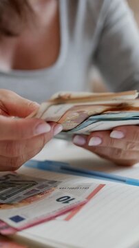 Close-Up Of Woman Counting Euro Money At Home Table In Vertical Video