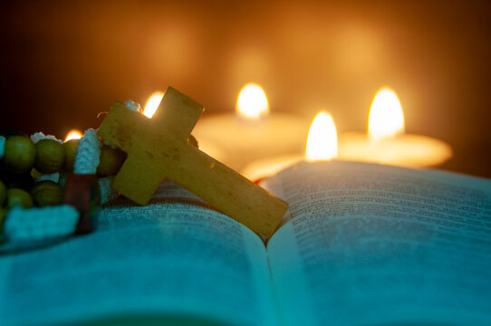 Blurred glowing candles with wooden crucifix representing faith and spiritual devotion with customizable space for text.