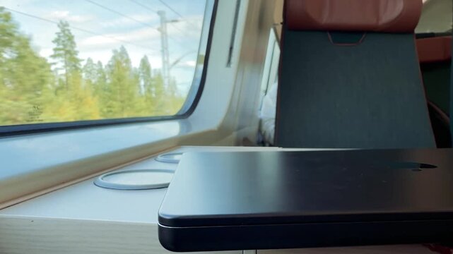 Empty Train Table by a Window with Forest Passing By