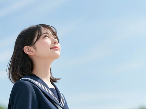 青空の下で未来への希望を胸に満面の笑みで上を見上げる女の子