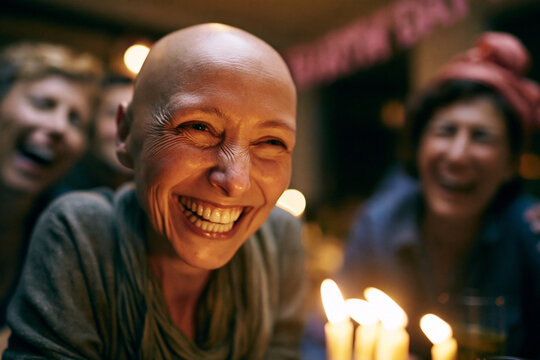 Joyful Bald Cancer Survivor Celebrating Birthday with Friends