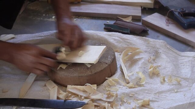 Artisan carving wood with chisel in traditional workshop setting