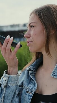 Vertical video. Woman holding phone speak activate virtual digital voice assistant on smartphone. Girl using smart phone voice recognition, dictates thoughts, voice dialing message.