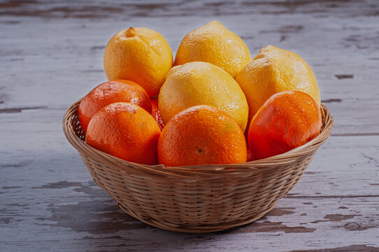 Fresh lemons and mandarins in a wicker basket on a rustic wooden table