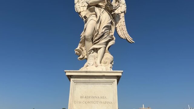 Low angle shot of Bernini angel statue on Ponte Sant&rsquo;Angelo with blue sky Rome