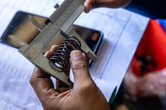 Mechanic Measuring Metal Coil Spring Length With Vernier Caliper Tool.