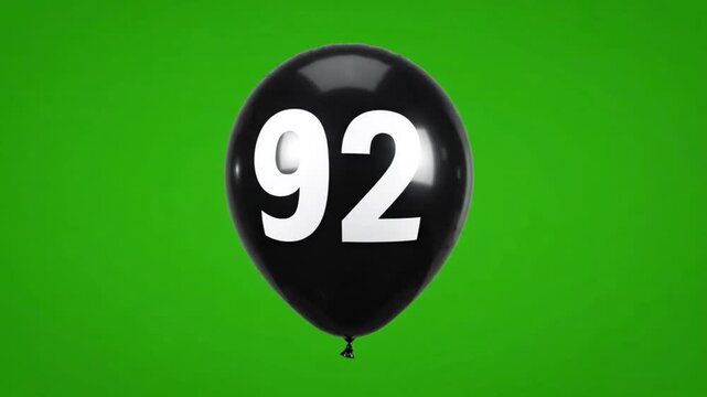 Black balloon with number 92 floating on green screen