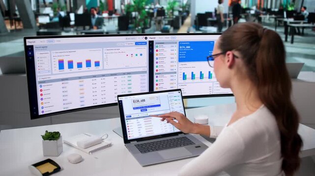 HR Manager Reviews Payroll Software On Laptop