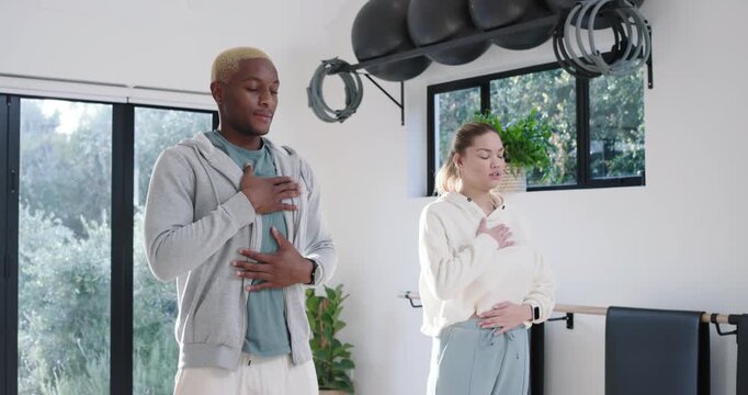 Diverse pair standing in gym cueing calming breathing opening eyes chatting greeting checking watch