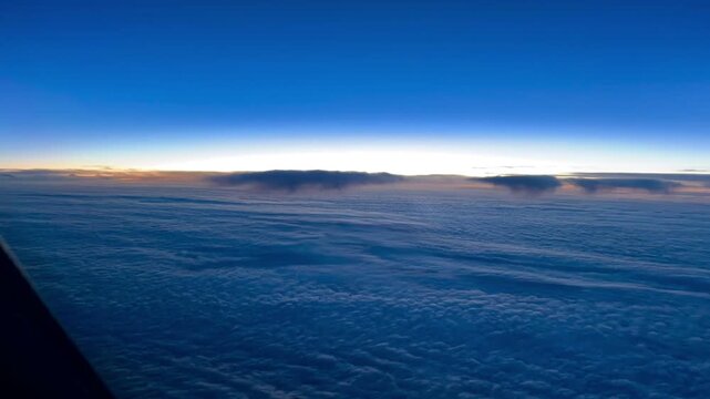 Dramatic 4K sunrise timelapse from a pilot&rsquo;s point of view at cruise altitude over the North Atlantic, with early morning light appearing along the horizon above an expansive cloud layer.