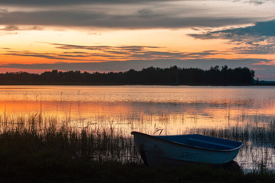 A peaceful boat resting on the calm lake at sunset.