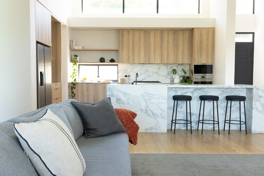 Grey fabric sofa is sitting on hardwood floor under clerestory windows, facing marble island