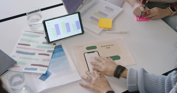 African American women in sweater arranging mockup noting colors after tablet chart in meeting
