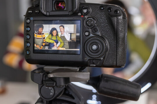 Diverse female friends wearing aprons filming in kitchen with DSLR on tripod, ring, mixing bowl