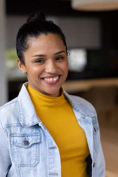 African American woman smiling, posing in kitchen wearing mustard turtleneck and jean jacket