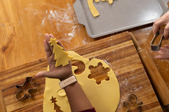 Rolled cookie dough sheet is resting on striped wooden cutting board with metal cutters and flour