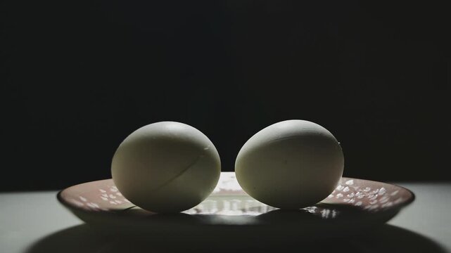 Changing Light and Shadows on White Eggs Against a Black Background