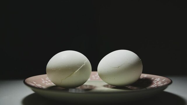 Changing Light and Shadows on White Eggs Against a Black Background