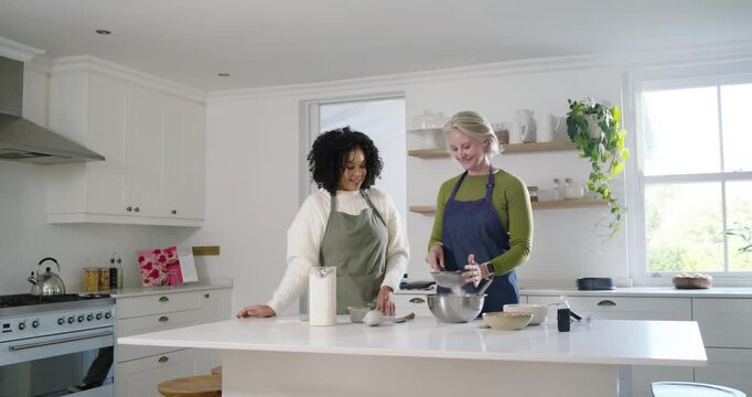 Diverse female friends measuring pouring whisking at white island with bowl and whisk