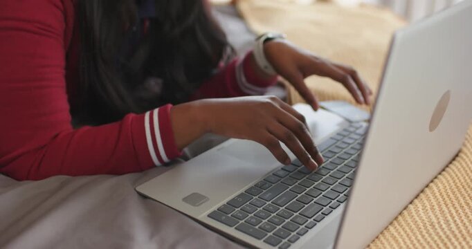 African American woman in red top typing on laptop, picking card, entering card details
